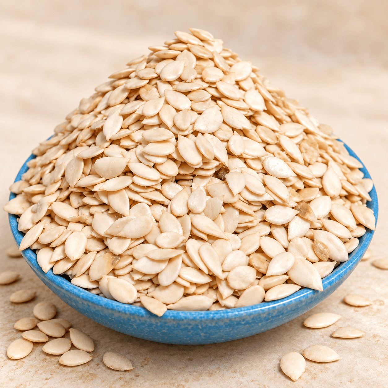 Whole egusi melon seeds piled in a blue bowl.