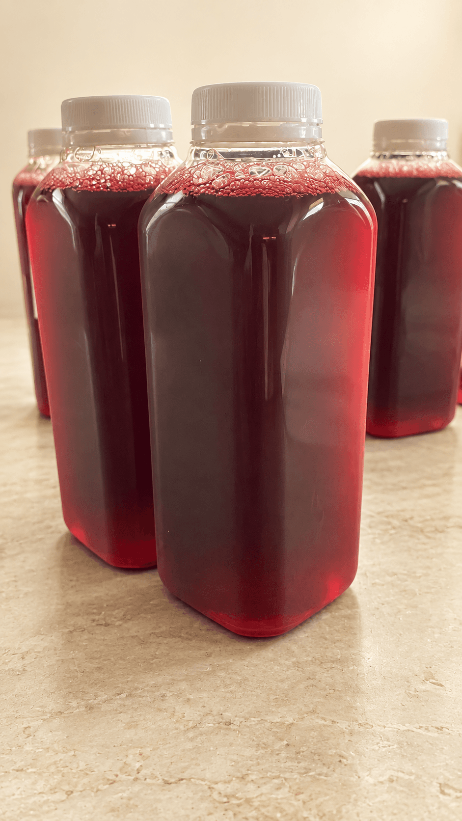 Bottles of deep-red Zobo drink with white caps.