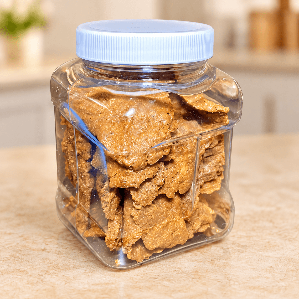 A white-lidded jar filled with golden Kuli Kuli peanut snacks.